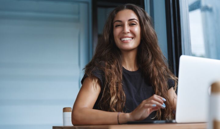 smiling-caucasian-woman-working-laptop-looking-happy-min