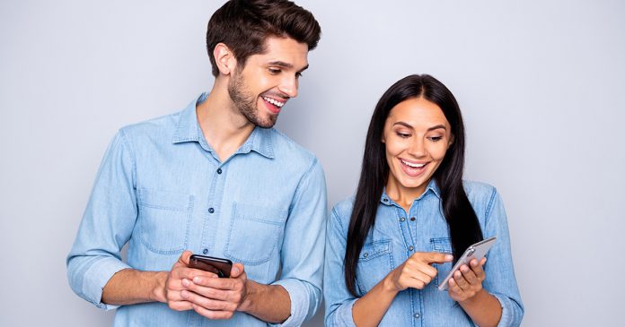 Portrait of his he her she nice attractive charming glad excited cheerful cheery couple holding in hands cell using 5g wi-fi connection speed isolated over light white gray pastel color background