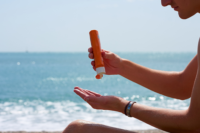 Zbliżenie na mężczyznę nakładającego krem ​​przeciwsłoneczny na plaży