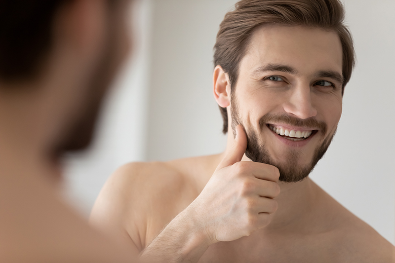 Pielęgnacja skóry męskiej - mężczyzna patrzy w lustro.