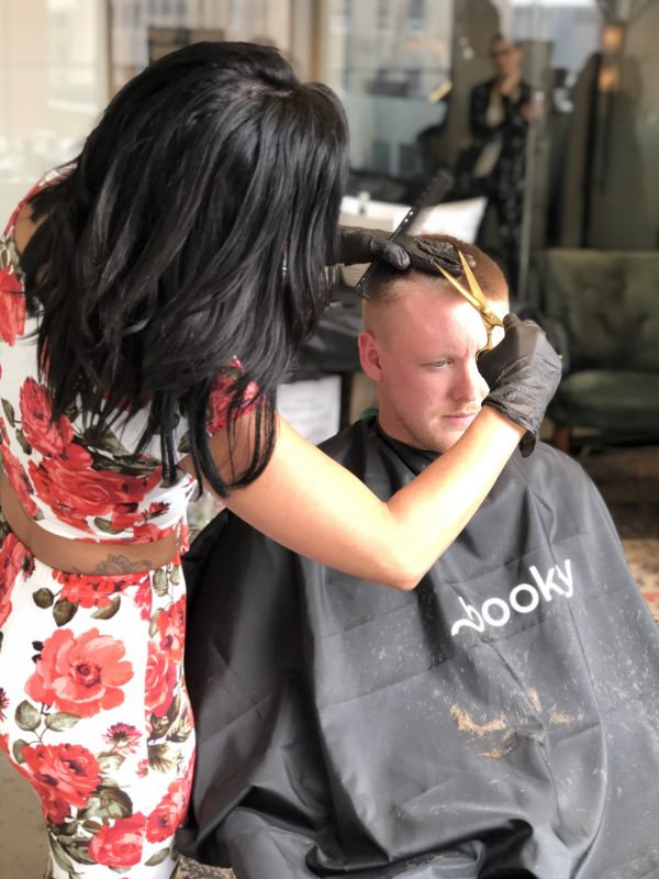 barber giving client a haircut with golden shears