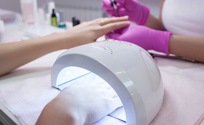 Women gets gel set manicure LED UV light curing