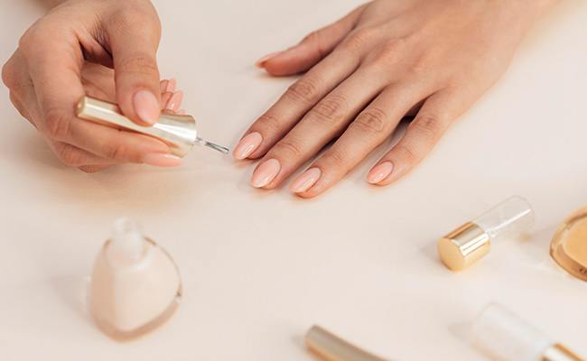 Woman applying classic pink nail polish